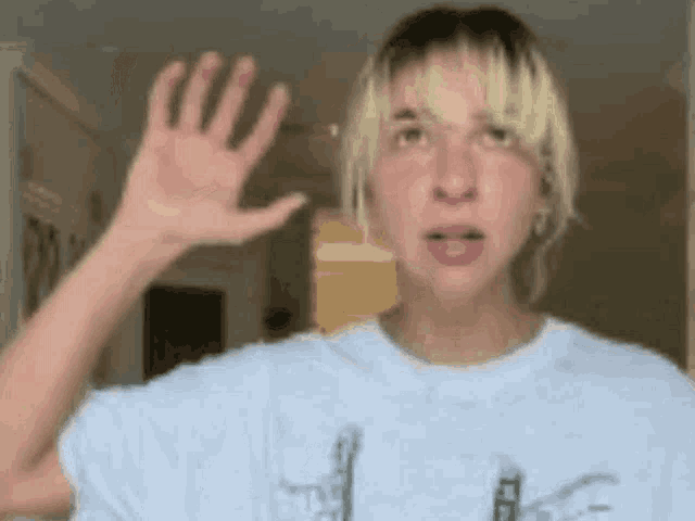 a woman in a white shirt is waving her hand in front of a window .