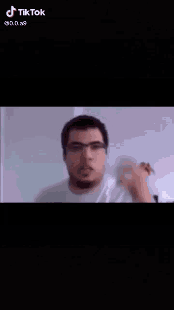 a man wearing glasses and a white shirt is making a funny face with his mouth open .
