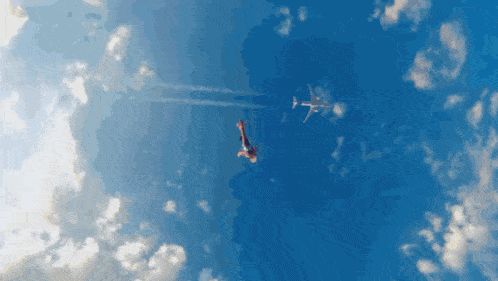 a person is falling through the air while a plane flies overhead