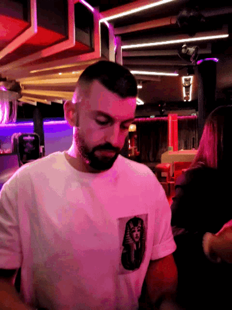 a man with a beard wears a white shirt with a picture of a pharaoh on the front