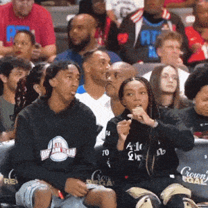 a group of people sitting in a stadium with one wearing a hoodie that says atl dream team
