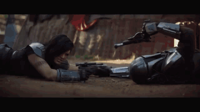 a man is laying on the ground holding a gun and another man is laying on the ground holding a gun