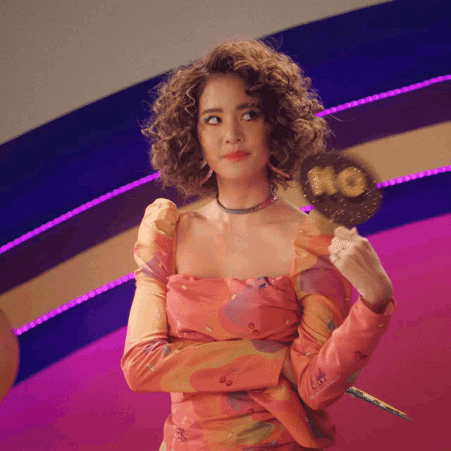 a woman in a floral dress is holding a lollipop that says no on it