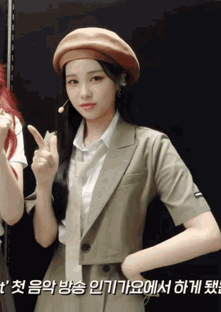 a woman wearing a beret and a suit giving the peace sign