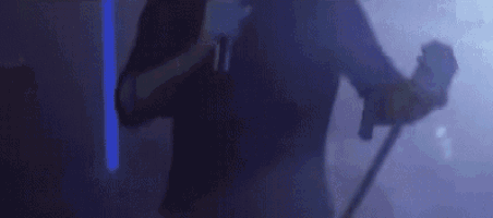 a man wearing a virtual reality headset is holding a microphone in a dark room .