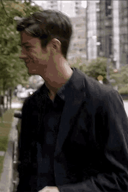a man in a suit and a blue shirt is walking down a sidewalk .