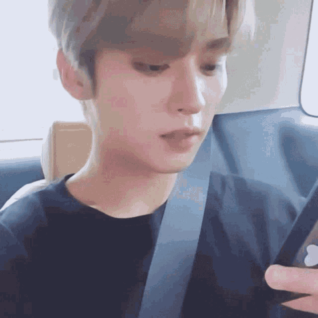 a young man is wearing a seat belt and looking at his cell phone