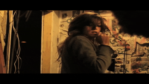 a woman is talking on a phone in front of a wall with posters on it including one that says ' a '
