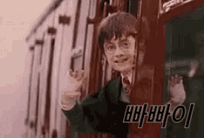 harry potter is waving from a train window .