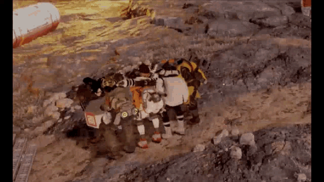 a group of firefighters are standing in a pile on top of a rocky hill .