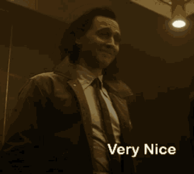 a man in a suit and tie is standing in a dark room and says very nice