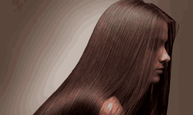 a woman with long brown hair is looking down at her hair