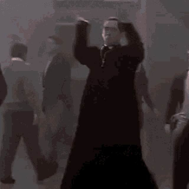 a woman in a black dress is dancing in a crowd