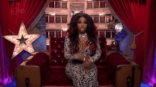 a woman is sitting in a chair in front of a stage with a star .