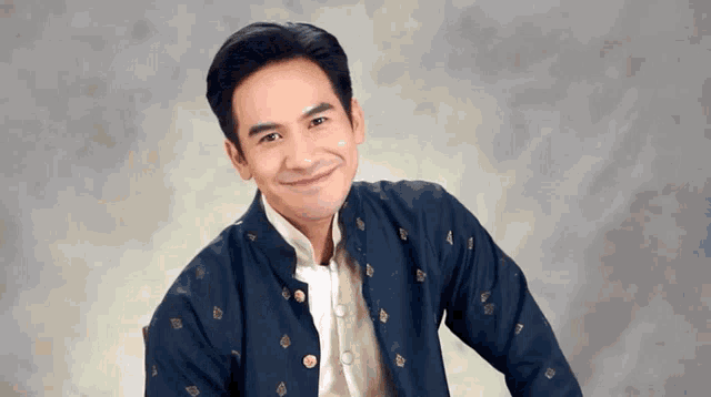 a man in a blue jacket and white shirt is smiling for the camera