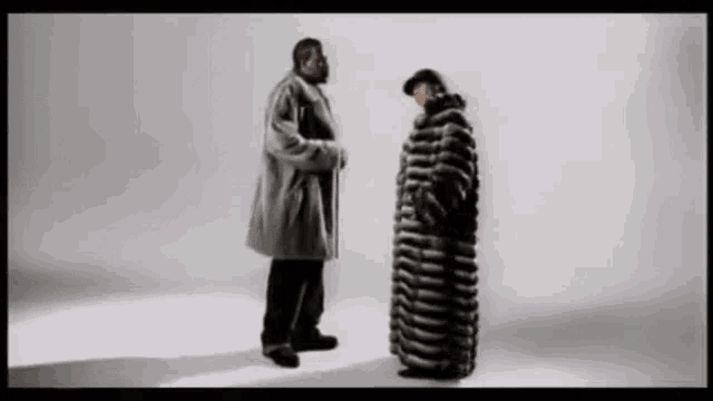 two men are standing next to each other and one is wearing a fur coat