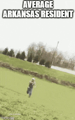 a man is running down a grassy hill with the words average arkansas resident above him .