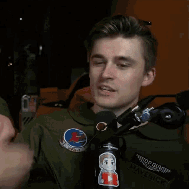 a man giving a thumbs up in front of a microphone that says topgun