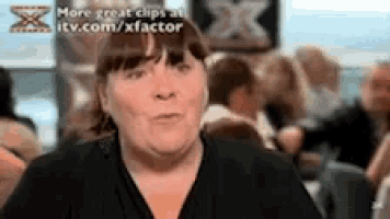 a woman in a black shirt is talking to a group of people in a restaurant .
