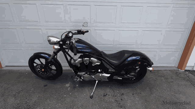 a blue motorcycle is parked in front of a garage door that says motorcyclist on it