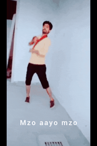 a man in a yellow shirt and black shorts is dancing in a room with the words mzo aayo mzo below him