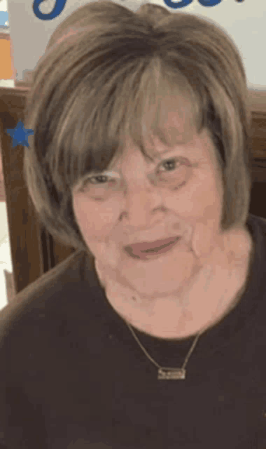 a close up of a woman 's face wearing a necklace and a brown shirt .