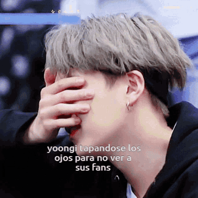 a close up of a person covering their face with a caption that says yoongi tapandose los ojos