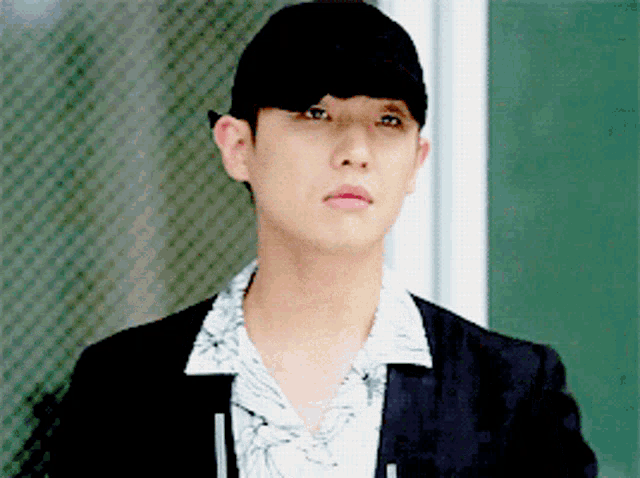 a man wearing a black hat and a white shirt looks at the camera