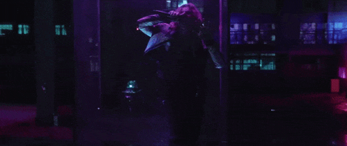a woman is standing in a dark room with purple lights behind her