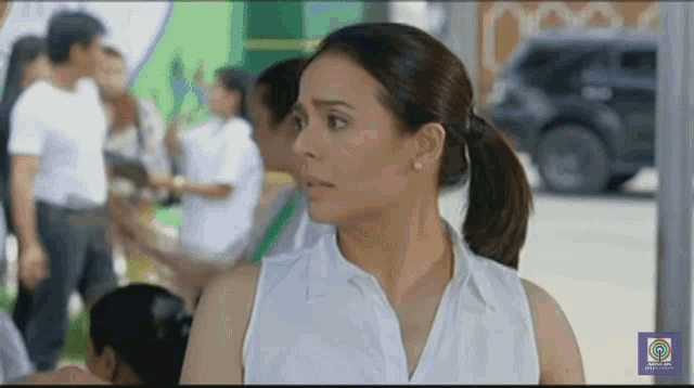 a woman in a white shirt is standing in front of a crowd of people