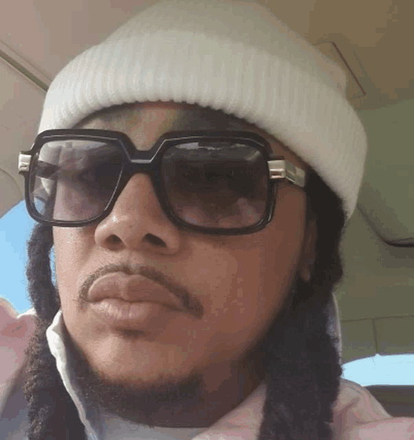 a man wearing sunglasses and a white beanie
