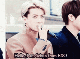 a man holding a microphone with the words hello i am sehun from exo below him