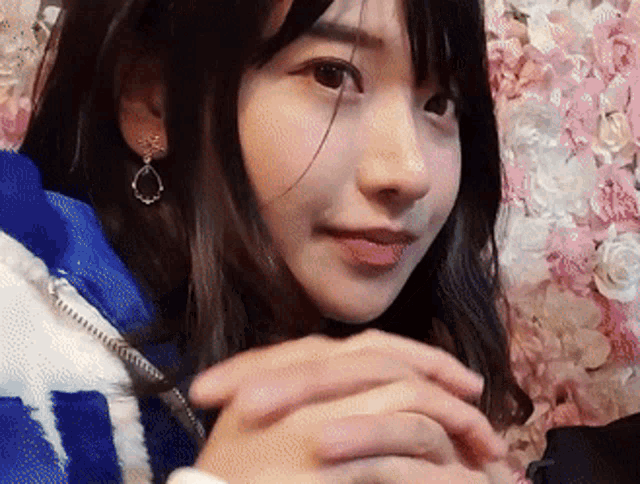 a close up of a girl 's face with flowers in the background