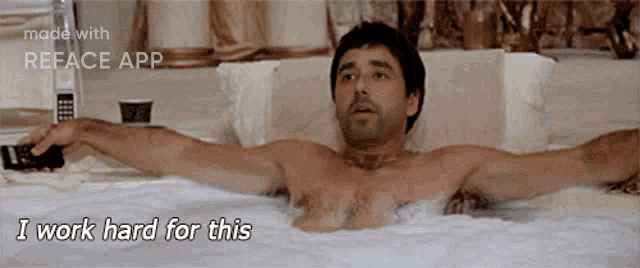 a shirtless man is laying in a bathtub with the words " i work hard for this " on the bottom