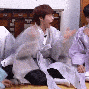 a group of people are sitting on the floor with one wearing a kimono
