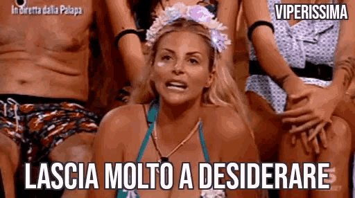 a woman in a bikini is sitting in front of a group of people and making a face .