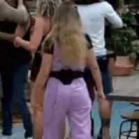 a woman in a purple jumpsuit is standing in front of a group of women .