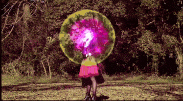 a girl in a pink skirt is standing in a field