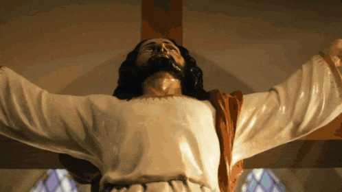 a statue of jesus with his arms outstretched in front of a stained glass window