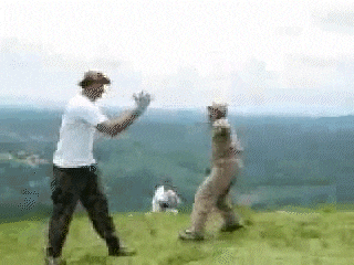 a couple of men are standing on top of a hill .