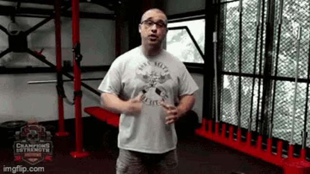 a man is standing in a gym wearing a t-shirt with a skull on it .