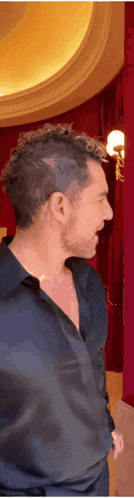 a man in a black shirt is standing in a room with a red wall .