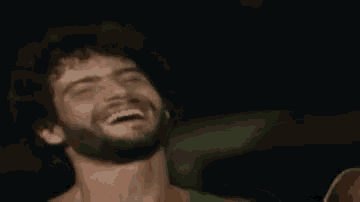 a man with a beard is laughing with his mouth open .