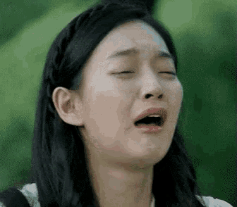 a woman is making a funny face with her mouth open and her eyes closed .