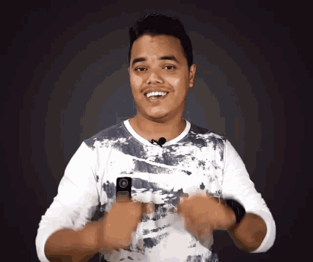 a man wearing a tie dye shirt with a microphone on his neck is smiling