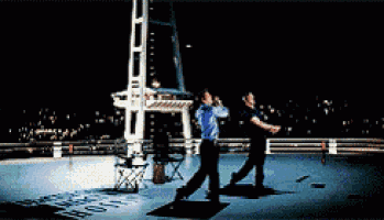 two men standing on a rooftop at night