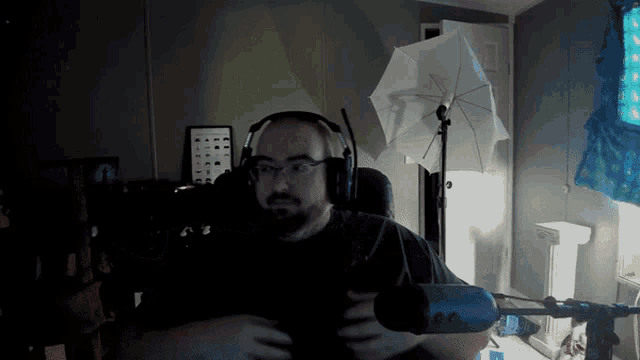 a man wearing headphones is sitting in front of a microphone in a dark room