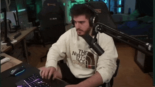 a man wearing headphones and a sweater that says the north face is typing on a keyboard