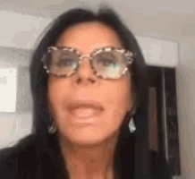 a woman wearing glasses and earrings is making a face .