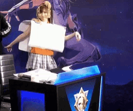 a woman holding a piece of paper in front of a podium that says ' league of legends ' on it